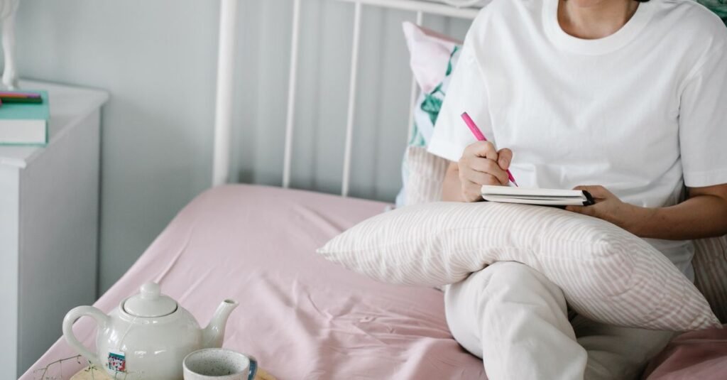 Woman journaling in a notebook beside her morning tea at home