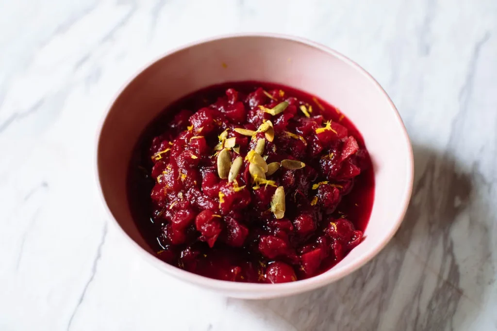 Cranberry sauce in a pink bowl with pumpkin seeds