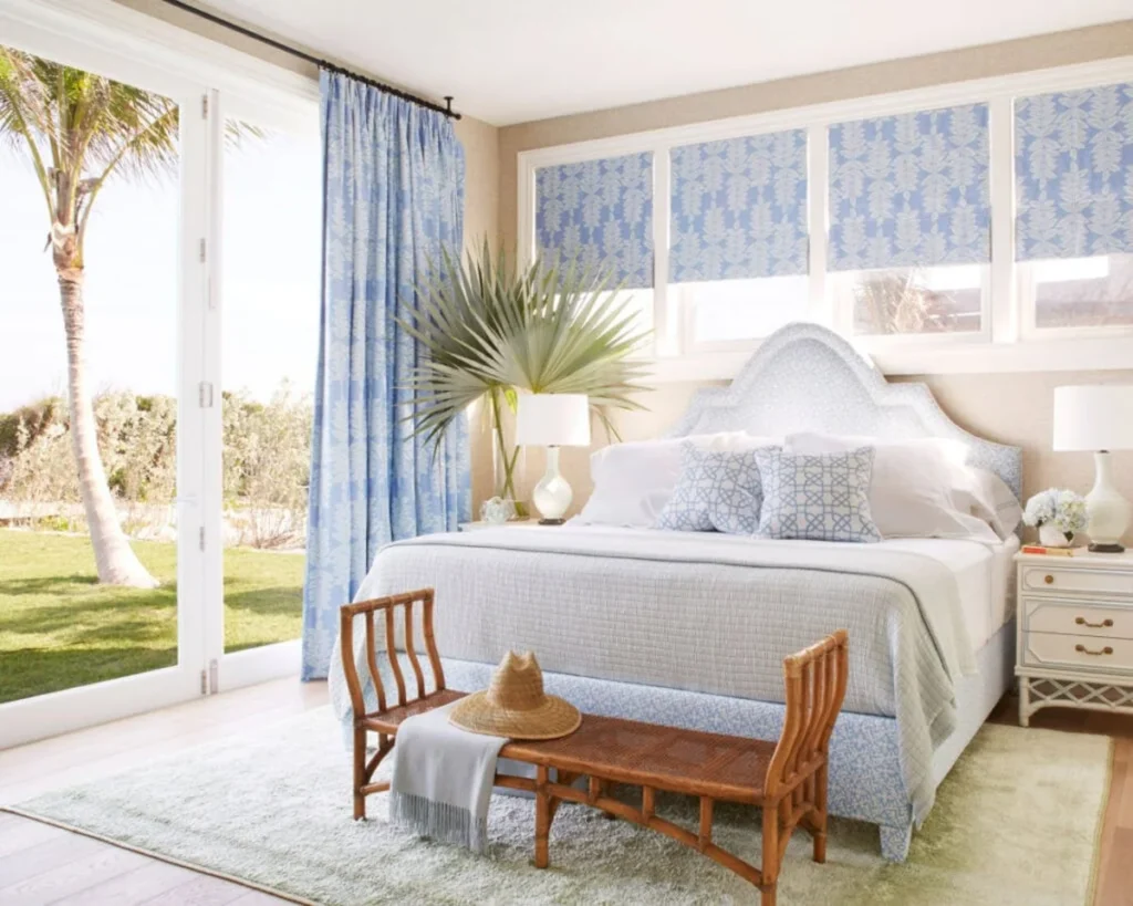 Bright coastal Bahamas bedroom with patterned blue bedding and rattan bench