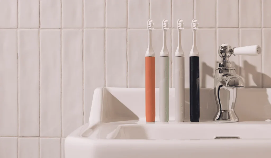 Colorful SURI electric toothbrushes standing upright on a white sink
