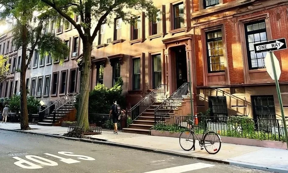 Brick row houses with stoops and a parked bicycle on a quiet city street