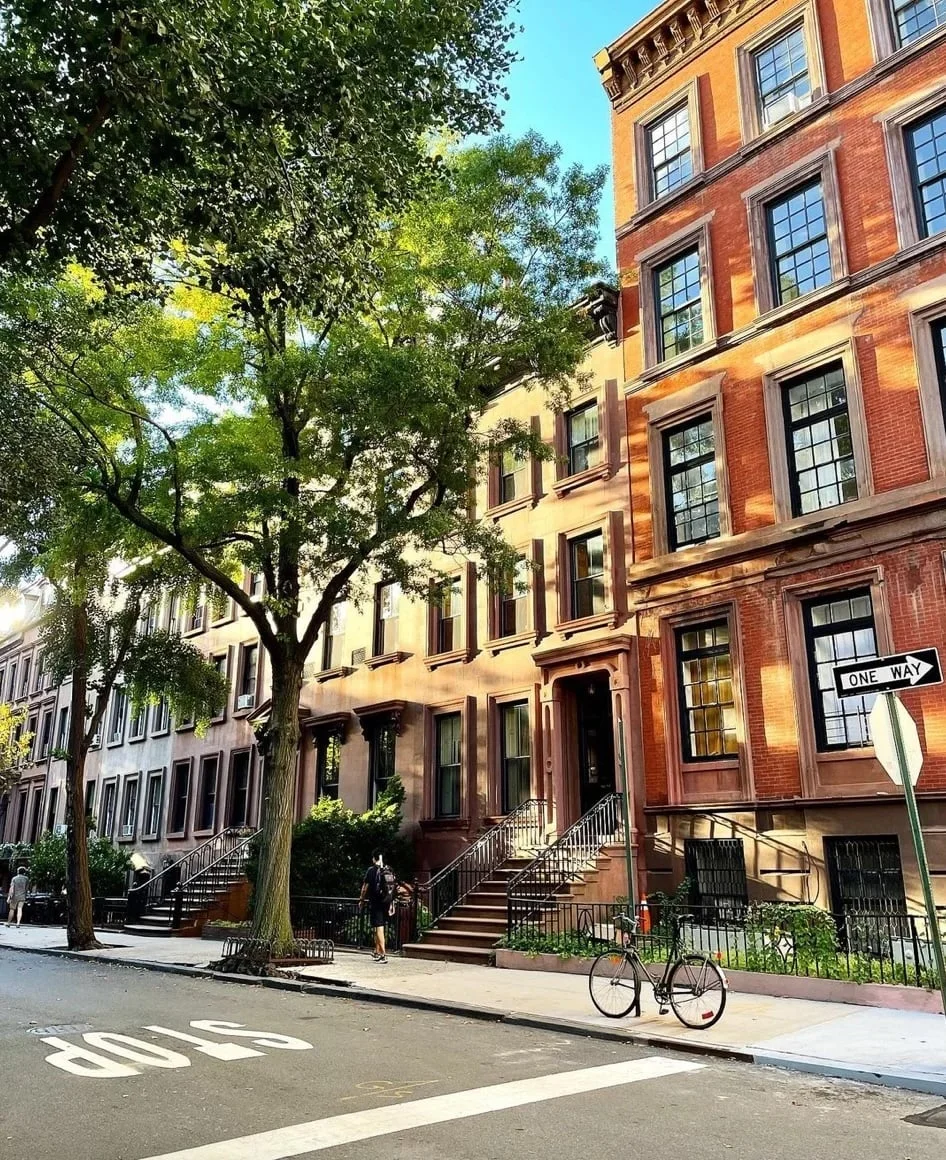 Row of historic brick townhouses with trees and a bicycle on a street