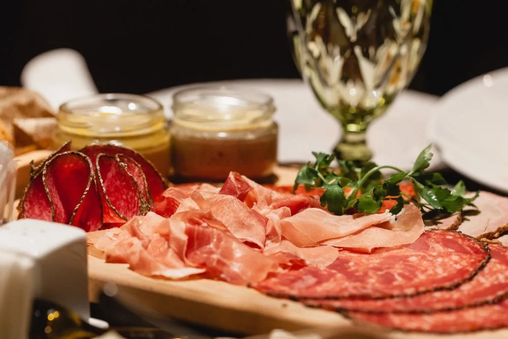 Wooden board of sliced cured meats garnished with fresh parsley