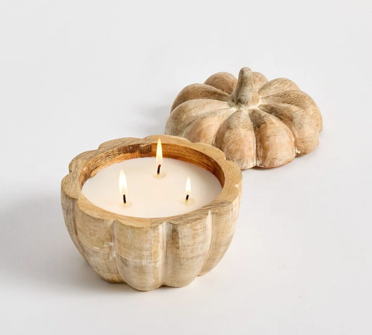 Lit three-wick candle in rustic wooden pumpkin holder with lid
